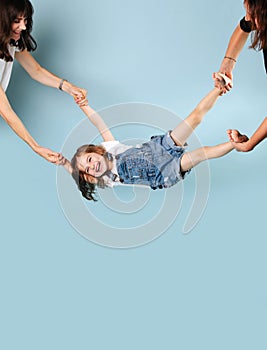 A girl in a denim jumpsuit is held by her legs and rocked