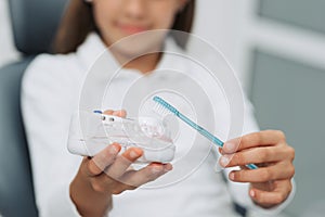 Girl in dentist chair showing how to clean teeth on dental jaw model at dental clinic. Dentistry, early prevention, oral hygiene