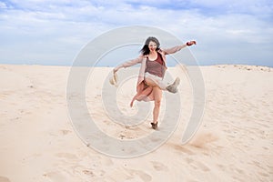 Girl in desert walk and  spills sand with hat and boots