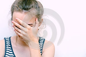 Girl in despair covers her face with hand. Stressed woman at home headache pain female portrait.