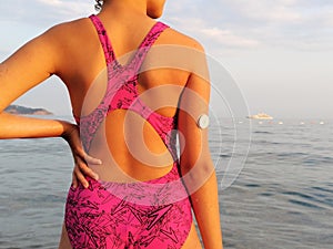 Girl with diabetes enters the sea. On the right arm is placed white sensor for continuous glucose monitoring in blood Ã¢â¬â CGM photo