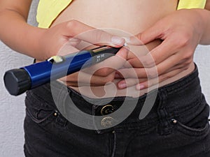 Girl with diabetes injects insulin from insulin pen in her belly photo