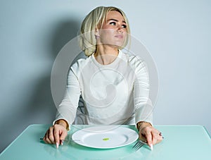 Girl on diet sits and eats a small portion of food