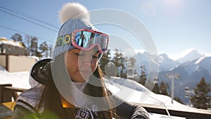 The girl dines at the restaurant on top of a mountain at a ski resort.