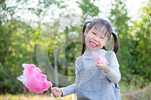 Girl with dirty mouth while eating pink cotton candy