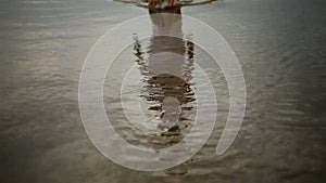 Girl disappearing into the sea at sunset