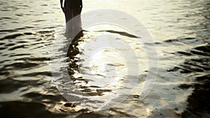 Girl disappearing into the sea at sunset