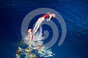 Girl dives off the shoulders of another girl in pool