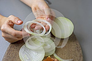 girl divides raw chopped onion into rings for vegetable salad.banana lies