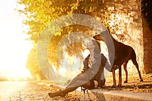 Girl with doberman. Beautiful young woman with dog at the sunset time at the street