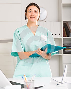 Girl doctor in medical coat holding clipboard with medical records