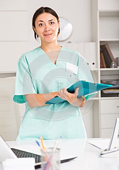 Girl doctor in medical coat holding clipboard with medical records