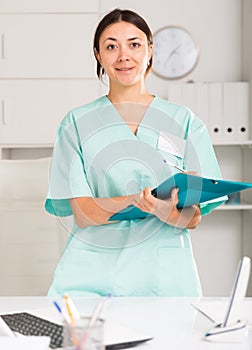 Girl doctor in medical coat holding clipboard with medical records