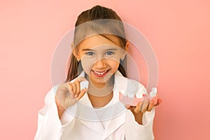 Girl in a doctor`s medical on hold a jaw model with a lost tooth