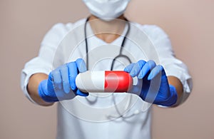 A girl doctor with a stethoscope, close-up holding a white red capsule