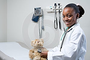 Girl doctor using stethoscope on teddy bear