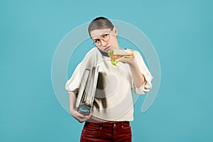 Girl with documents under her armpit is talking on the phone and is about to eat