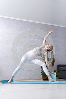 Girl does exercises at home on yoga mat with foam block. Yoga practice for beginners. Young woman using yoga bricks