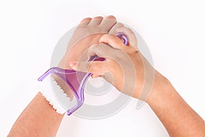 A girl does a hand massage with hand massager on a white background. Top view