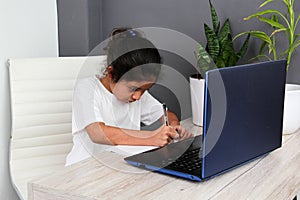 Girl does home schooling takes online classes at home on a desk with a laptop, studies, is surprised and participates in class