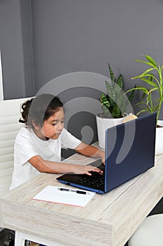 Girl does home schooling takes online classes at home on a desk with a laptop, studies, is surprised and participates in class