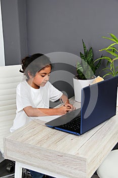 Girl does home schooling takes online classes at home on a desk with a laptop, studies, is surprised and participates in class