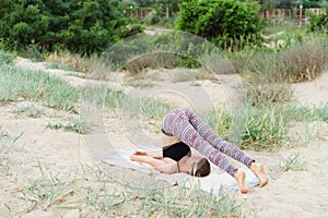 Girl does inverted yoga asanas in the outdoor, the plow pose