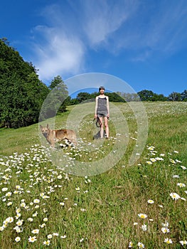 Girl with dog among chamomile field