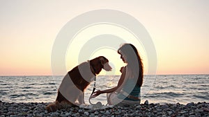 Girl and dog gaze over the sea at sunset, serene companionship