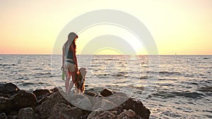 Girl and dog gaze over the sea at sunset, serene companionship