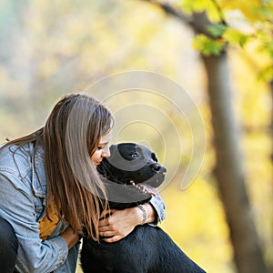 Girl with dog labrodor in autumn park at sunset