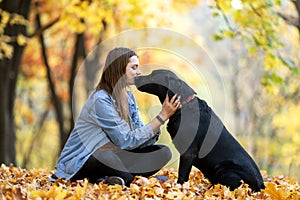 Girl with dog labrodor in autumn park at sunset