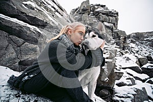 Girl with dog Malamute among rocks in winter. Close up.