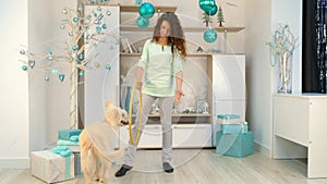 Girl with a dog is playing with a hoop in room with Christmas decorations