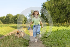Girl with dog running in park, summer field. child playing with puppy outdoors.