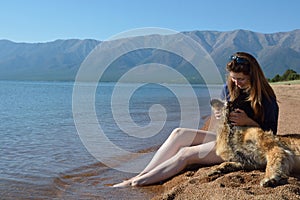 Girl with a dog is on the shore of Lake Baikal