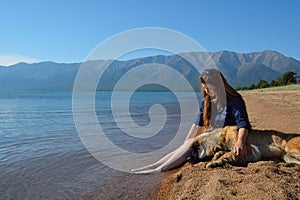 Girl with a dog on the shore of Lake Baikal