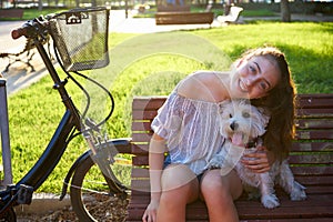 Girl with dog sitting in a park bench