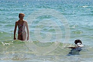 Girl with dog swimming in the sea