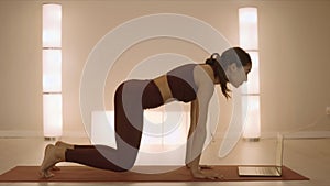 Girl doing childs pose in yoga studio. Woman looking video on laptop computer