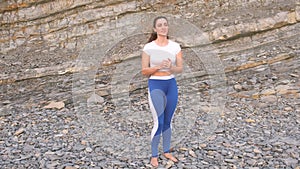 Girl is doing exercise lunge, leg lift the bodyflex during breathing exercises on the rock background.