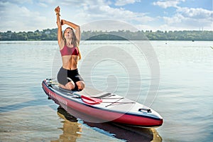 The girl is doing exercises fitness on SUP board on the water, the atmosphere of relaxation