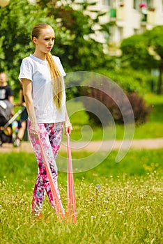 Girl doing exercises outdoor, using resistance fit band