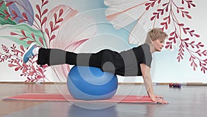 Girl doing fitness exercises on a sports equipment big ball in the hall