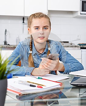 Girl doing home task using mobile phone