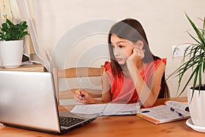 Girl doing homework and watching webinar at laptop.  Distance education, homeschooling, E-learning at home during quarantine