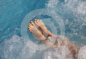 Girl doing the hydromassage in the pool of the spa