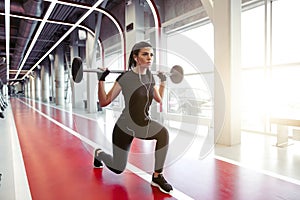 Girl doing lunges with barbell in modern gym