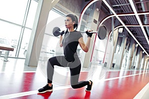 Girl doing lunges with barbell in modern gym