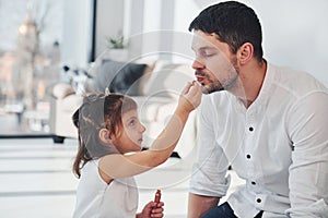 Girl doing make up for dad. Happy father with his daughter spending free time at home together